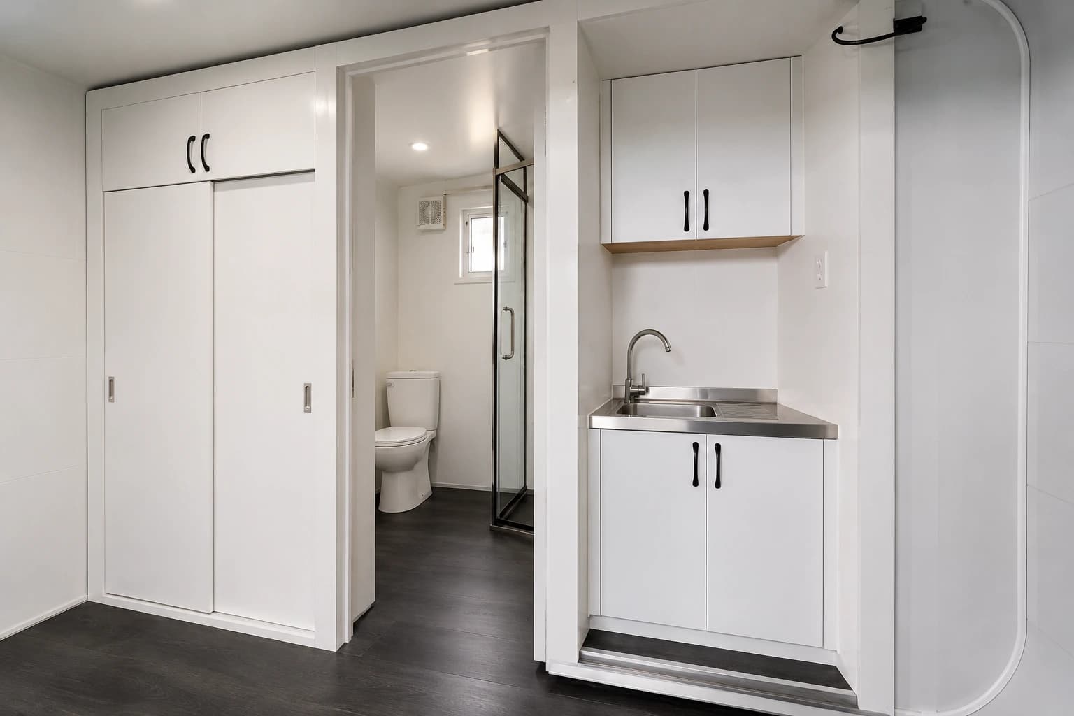 Interior detail — the bathroom with shower and toilet beside a compact kitchenette