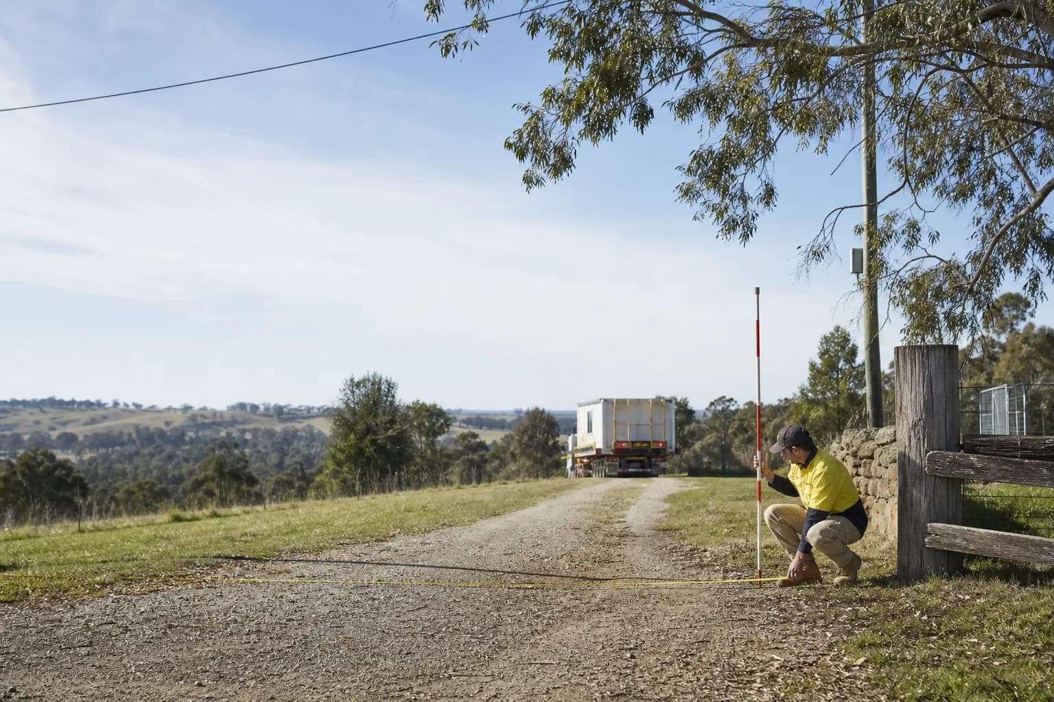Site assessor measuring a rural driveway entrance for modular home transport access