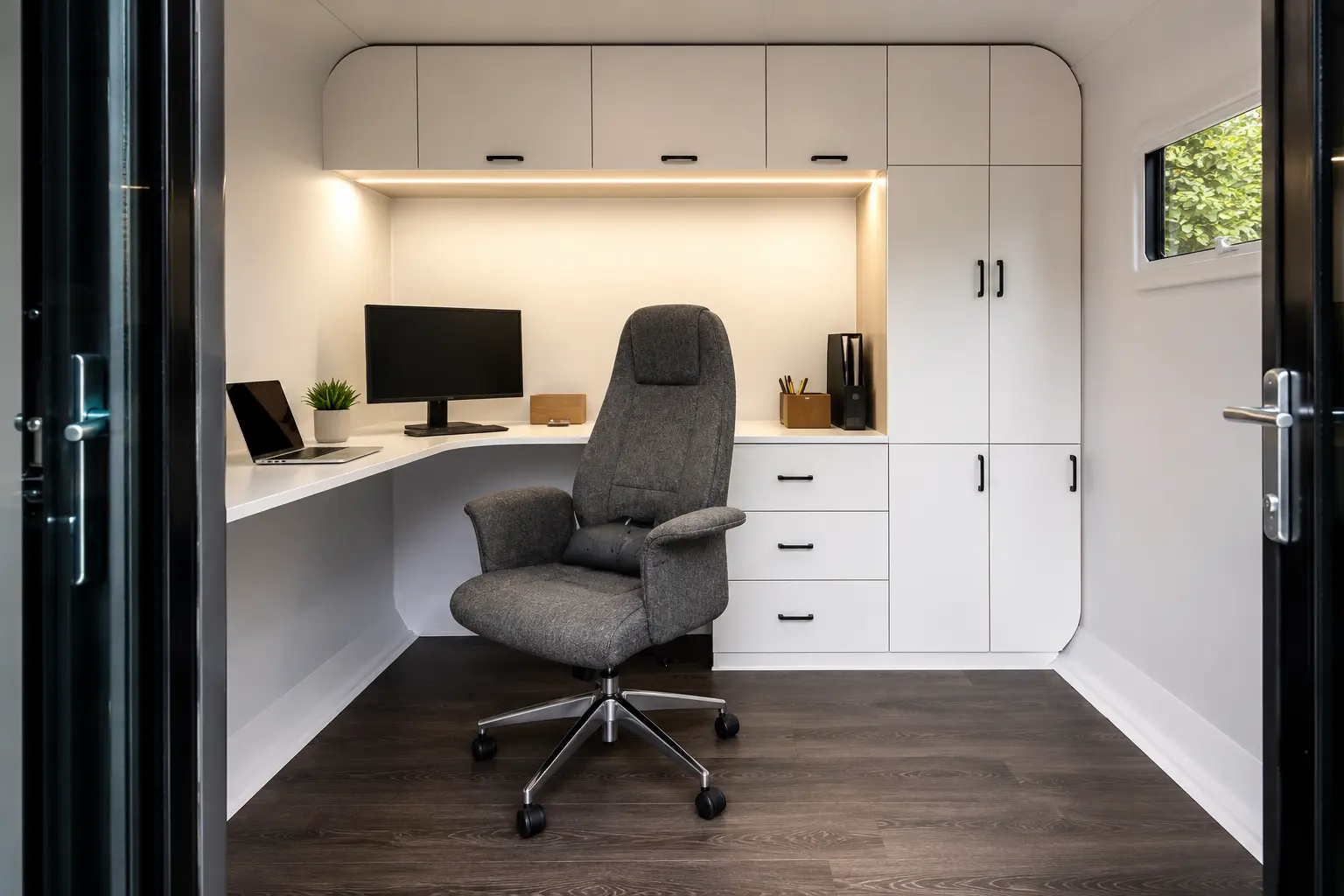 Inside the pod — a wrap-around desk, integrated cabinetry and a soft office chair under warm lighting